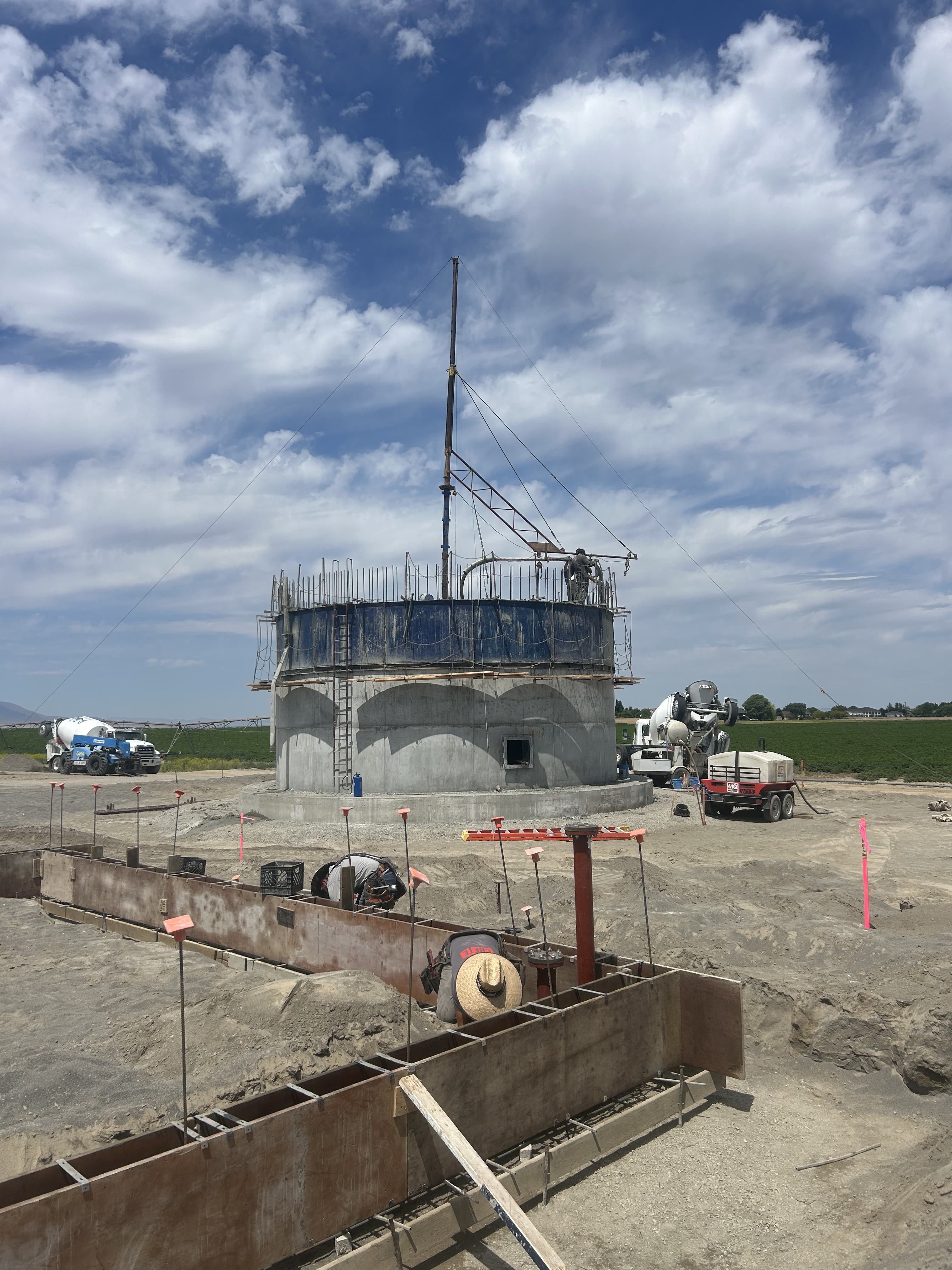 Water treatment concrete tank under construction — scaffolding, rebar formwork, and cement truck on site